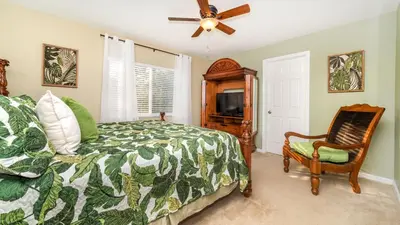 a bedroom with a bed and a fan and a chair at 2696 Manesty in Kissimmee