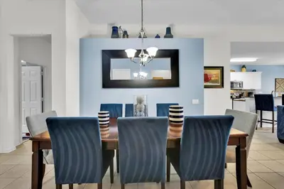 a dining room with a wooden table and blue chairs at 2702 Manesty in Kissimmee