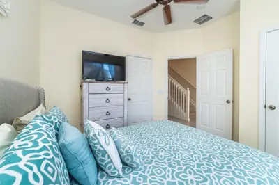 a bedroom with a bed with blue pillows and a tv at 2505 Maneshaw in Kissimmee