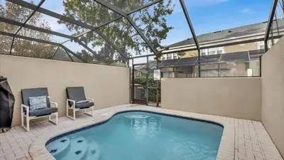 a swimming pool with two chairs and a house at 7679 Sir Kaufman in Kissimmee