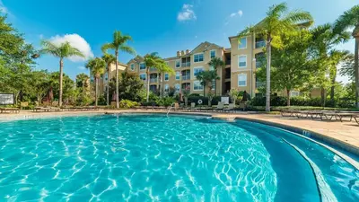 a swimming pool with palm trees and condos at 7679 Sir Kaufman in Kissimmee