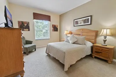 a bedroom with a bed and a television and a chair at 8107 Coconut Palm #305 in Kissimmee
