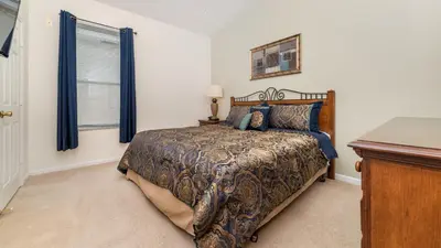 a bedroom with a bed with blue curtains and a desk at 8104 Fan Palm in Kissimmee