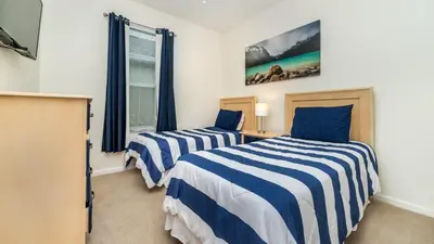 a bedroom with two beds with blue and white striped sheets at 8104 Fan Palm in Kissimmee