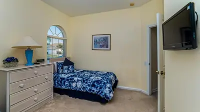 a bedroom with a bed and a dresser with a tv at 8147 Fan Palm in Kissimmee
