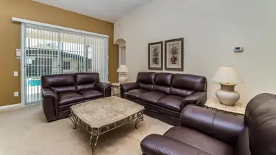 a living room with leather furniture and a large window at 8147 Fan Palm in Kissimmee