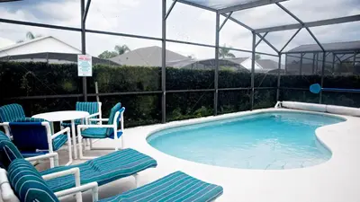 a large swimming pool with chairs and a table at 8159 Fan Palm in Kissimmee