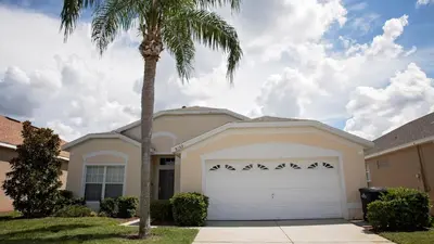 a palm tree in front of a house with a garage at 8159 Fan Palm in Kissimmee