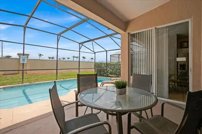 a patio with a table and chairs and a pool at 8190 Fan Palm in Kissimmee