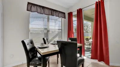 a dining room with red curtains and a table and chairs at 8034 King Palm in Kissimmee