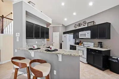 a kitchen with black cabinets and a counter with chairs at 8038 King Palm in Kissimmee