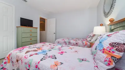 a bedroom with two beds and a dresser with a bedspread with flowers at 8135 Sun Palm in Kissimmee