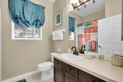 a bathroom with a sink and a toilet and a window at 2302 Silver Palm # 103 in Kissimmee