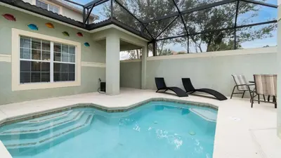 a swimming pool with chairs and a house at 8949 Candy Palm in Kissimmee