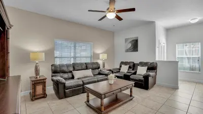 a living room with leather furniture and a ceiling fan at 8967 Cat Palm in Kissimmee
