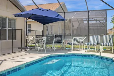 a pool with chairs and a table with an umbrella at 201 Hideaway beach 4 beds - pool&spa in Kissimmee