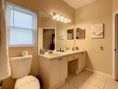 a bathroom with a toilet and a sink and a mirror at Beautiful Windsor Palms 4 Bed South Facing Pool villa in Kissimmee
