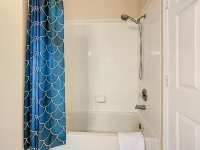 a bathroom with a shower with a blue shower curtain at Beautiful Windsor Palms 4 Bed South Facing Pool villa in Kissimmee