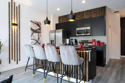 a kitchen with a bar with white stools in it at Marvelous 3Bd Close to Disney w GameRoom at The Hub 3409 in Kissimmee