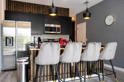 a kitchen with a bar with four white stools at Marvelous 3Bd Close to Disney w GameRoom at The Hub 3409 in Kissimmee