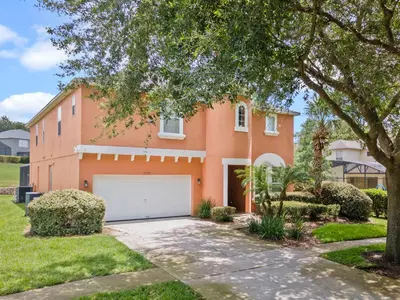 a large orange house with a white garage at Be-Our-Guest Home! 15 mins to Disney! in Kissimmee
