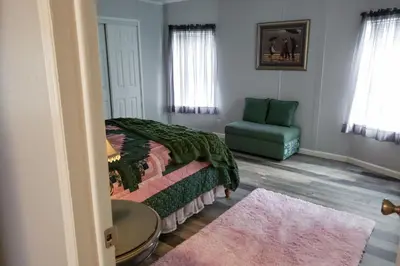a bedroom with a bed and a green chair at Sanford Country Escape Fire Pit, Yard and Wildlife! in Sanford