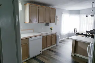 a kitchen with wooden cabinets and a white dishwasher at Sanford Country Escape Fire Pit, Yard and Wildlife! in Sanford