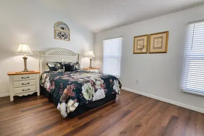 a bedroom with a bed and wooden floors and windows at Clear Creek 3 Bedroom Home Private Pool 15 Min to Disney in Orlando