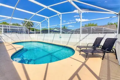 a swimming pool with two chairs next to a fence at Clear Creek 3 Bedroom Home Private Pool 15 Min to Disney in Orlando