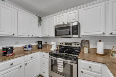a kitchen with white cabinets and a stove and microwave at 2BR condo minutes to Disney Springs in Orlando