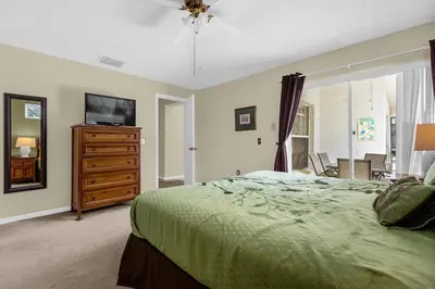 a bedroom with a bed and a dresser and a television at 1061 Lake Berkley 4 Bed with Pool&Spa in Kissimmee