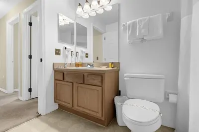 a bathroom with a toilet and a sink and a mirror at 1061 Lake Berkley 4 Bed with Pool&Spa in Kissimmee