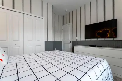 a white bedroom with a bed and a flat screen tv at Luxurious Home w Theme Beds & Private Pool in Kissimmee
