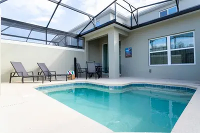 a swimming pool with chairs and a house at Luxurious Home w Theme Beds & Private Pool in Kissimmee