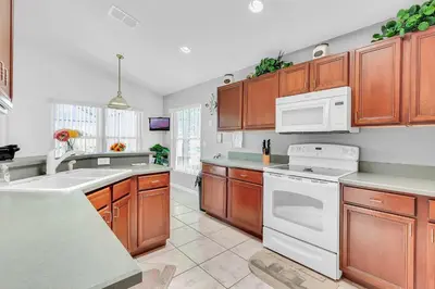 a kitchen with wooden cabinets and white appliances at 4 bedrooms pool home with water view and short drive from Disney in Kissimmee