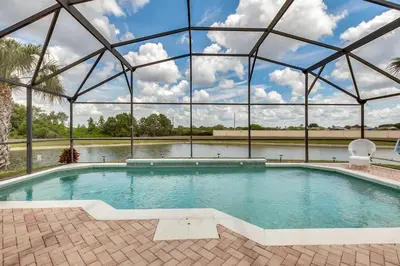 a large swimming pool with a large glass building at 4 bedrooms pool home with water view and short drive from Disney in Kissimmee