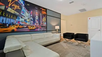 a living room with a white couch and a large screen at Storey Lake 6BR Cozy Home Private Pool Near Disney in Kissimmee