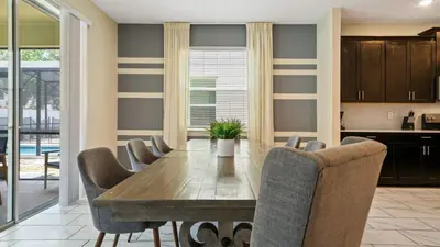 a kitchen and dining room with a wooden table and chairs at Storey Lake 6BR Cozy Home Private Pool Near Disney in Kissimmee