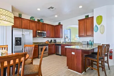 a kitchen with wooden cabinets and a table and chairs at 6BR Private Pool, Spa, Gameroom, Close to Disney in Orlando
