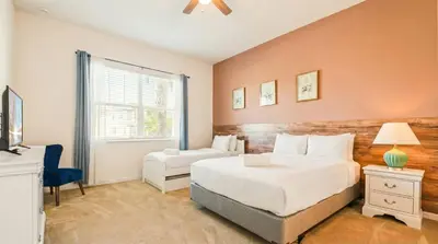 a bedroom with two beds and a desk and a window at Spacious 12-Bed Villa with Pool & Resort Amenities in Kissimmee