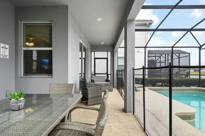 a patio with a table and chairs and a swimming pool at Lakeview 6BR Cozy Home Pool/SPA,Steps to Waterpark in Kissimmee