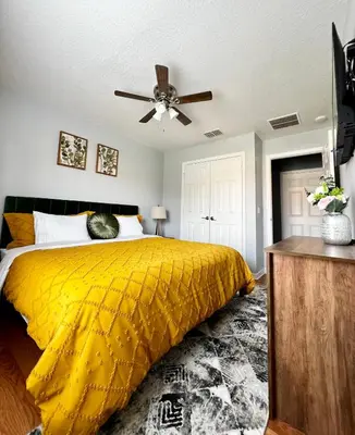 a bedroom with a yellow bed with a ceiling fan at Stylish 3 bd townhouse near Disney with private pool. in Kissimmee