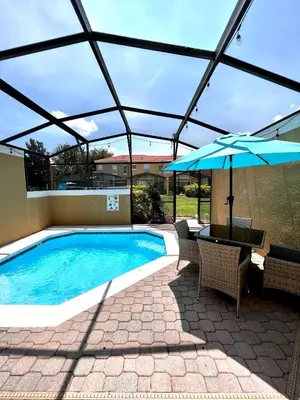 a patio with a pool and an umbrella and a table at Stylish 3 bd townhouse near Disney with private pool. in Kissimmee