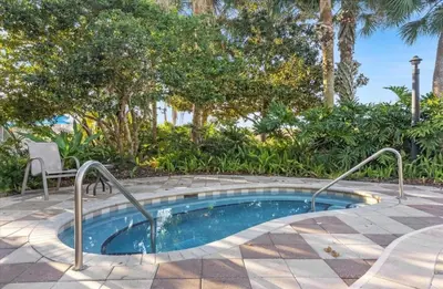 a small pool in a patio with a chair and trees at Stylish 3 bd townhouse near Disney with private pool. in Kissimmee