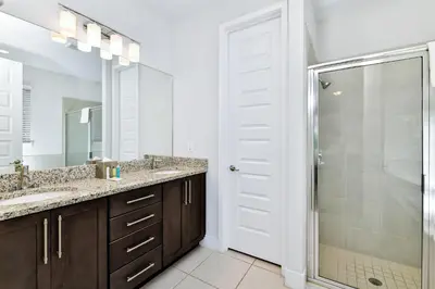 a bathroom with two sinks and a shower with a glass door at Elegant Home With Private Pool, Waterpark & Resort Access Near Disney At Encore Resort - 7610Wi in Kissimmee