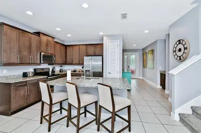 a kitchen with a table with chairs and a counter top at Elegant Home With Private Pool, Waterpark & Resort Access Near Disney At Encore Resort - 7610Wi in Kissimmee