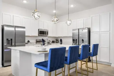 a kitchen with a large island with blue chairs at Game Room 12BR Kids World Pool Spa Near Disney in Kissimmee