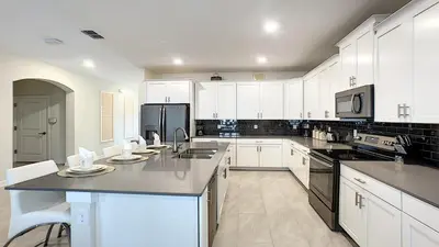 a large kitchen with white cabinets and appliances at Cozy Home Storey Lake Resort Pool Spa Near Disney in Kissimmee