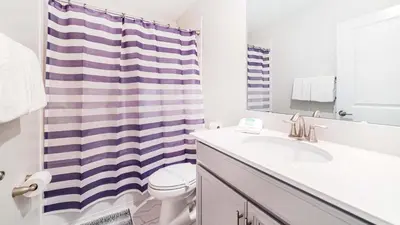 a bathroom with a sink and a shower curtain at Family Oasis: Pool, Themed Rooms & Resort Access in Kissimmee