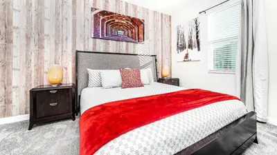 a bedroom with a large bed with a red blanket at Family Oasis: Pool, Themed Rooms & Resort Access in Kissimmee